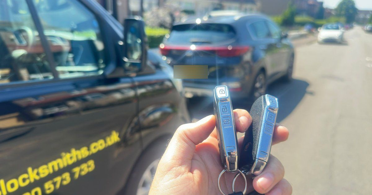 Two Kia smart keys held in hand next to the LKC Locksmiths van in Greenock